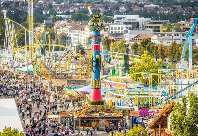 Vogelperspektive auf die Fruchtsäule mit einer Menschenmenge auf den Wegen drumherum und einer Achterbahn im Hintergrund